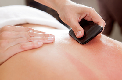 An up close view of a Gua Sha massage using a special instrument.